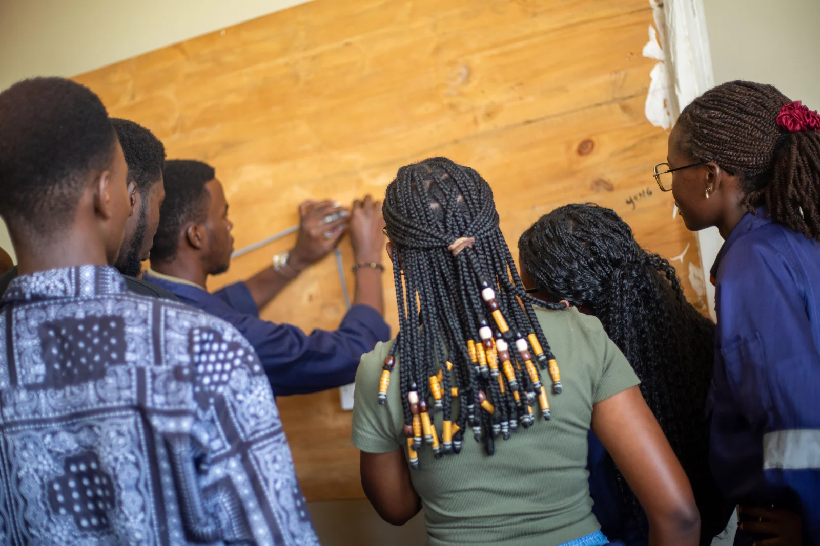 Students measuring and wiring a circuit board in a workshop